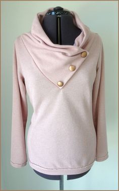 a pink sweater with gold buttons on the front and bottom, next to a mannequin torso