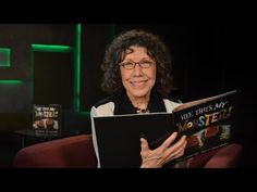 a woman reading a book while sitting in a chair with her hands on the cover