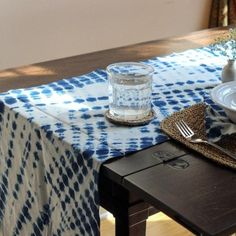 a table with a blue and white checkered table cloth on it, next to a glass vase filled with flowers