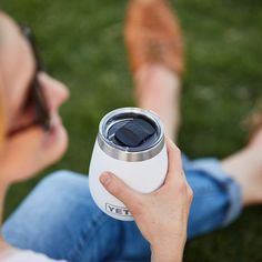 a woman is holding a yeti water bottle in her hand while laying on the grass