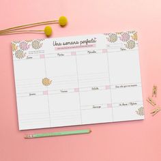 a pink and white desk calendar with gold confetti on it next to a green pencil