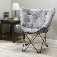 a grey chair sitting on top of a hard wood floor next to a night stand