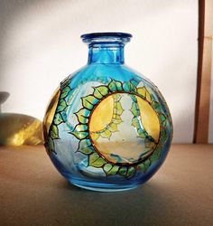 a blue glass vase sitting on top of a wooden table next to a lamp shade