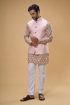 Peach sleeveless bundi crafted in cotton silk. Paired with an ikat print kurta and pant. - Aza Fashions Luxury Ikat Print Kurta For Festivals, Transitional Sleeveless Cotton Kurta, Fitted Cotton Silk Nehru Jacket For Spring, Fitted Nehru Jacket In Cotton Silk For Spring, Sleeveless Cotton Kurta, Traditional Ikat Print Patterned Kurta, Traditional Pink Cotton Nehru Jacket, Ikat Kurta Men, Unstitched Multicolor Ikat Print Kurta