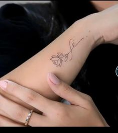 a woman's left arm with a small tattoo on it, and her right hand holding the wrist