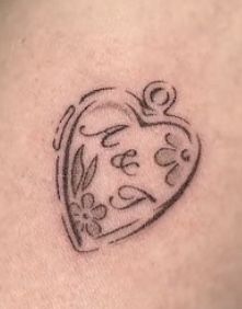 a small tattoo on the back of a woman's shoulder with a heart and flowers