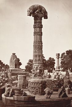 an old black and white photo of a statue in the middle of a park with statues around it