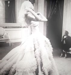 an old photo of a woman in a wedding dress with feathers on it's skirt