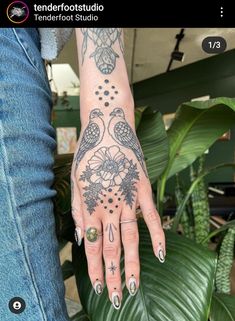 a woman's hand with tattoos on it, and two birds in the middle