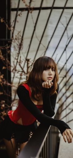 a woman leaning on a railing with her hand under her chin