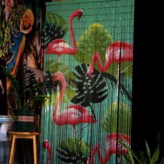 a green screen with pink flamingos painted on it next to a potted plant