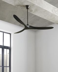 a ceiling fan is hanging from the ceiling in a room with white walls and windows