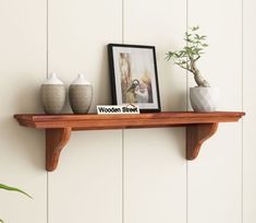 there is a wooden shelf with three vases and a framed photo on the top