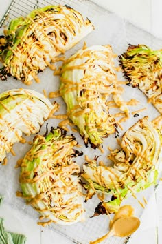 grilled artichokes on a baking sheet with sauce drizzled over them