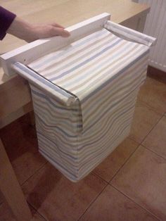 a person holding a box on top of a wooden table next to a wall mounted radiator