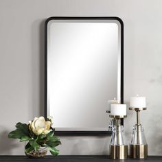 a mirror sitting on top of a wooden table next to candles and a vase with flowers