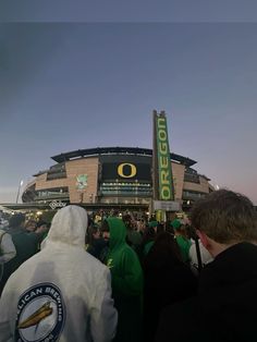 a group of people standing in front of a stadium with green and white hoodies