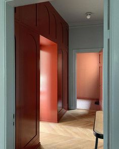 an empty room with red cabinets and a bench in the middle is seen through a doorway