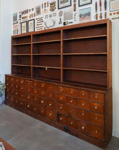 an old dresser with many drawers and pictures on the wall