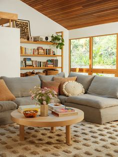 a living room filled with furniture and bookshelves next to a window covered in plants