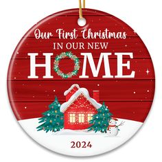 a christmas ornament with a red house and wreath on it, saying our first christmas in our new home