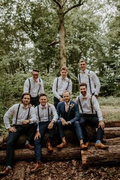 a group of men sitting on top of a tree log in the middle of a forest