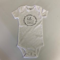 This is a white bodysuit that says Hello Little Wildflower.  Great for that little one of yours or for a gift! The designs we offer are created by hand, so please allow for slight variation in design placement. Please allow 3-7 business days for production.  Please feel free to contact me with any questions.  Thank you for shopping with us! Follow us on Facebook at facebook.com/williamandwesley.  To continue browsing graphic shirts, click here: https://www.etsy.com/shop/WilliamandWesley White Short Sleeve Onesie For Spring, White Cotton Onesie As A Gift, Cute White Short Sleeve Bodysuit, Casual Personalized White Onesie, Casual White Personalized Onesie, Cute White Bodysuit With Name Print, Cute White Bodysuit With Letter Print, White Cute Bodysuit With Name Print, Fitted White Short Sleeve Bodysuit With Letter Print