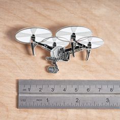 two small white propellers sitting on top of a wooden table next to a measuring ruler