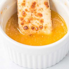 a white bowl filled with soup and two pieces of bread sticking out of the top