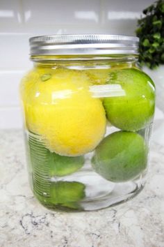 a jar filled with lemons and limes on top of a marble countertop