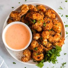 fried cauliflower with dipping sauce in a white bowl on a marble countertop