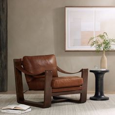 a brown leather chair sitting next to a table with a vase on top of it