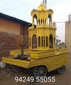 an elaborately designed yellow cart sits in front of a brick building