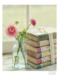 a vase filled with pink flowers next to books