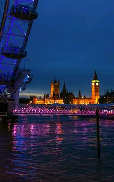 the big ben clock tower towering over the city of london at night with lights reflecting in the water