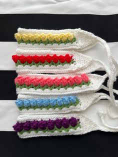 four crocheted headbands with different colored flowers on them, lined up against a black and white striped background