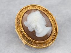 Crafted in the 1800s, this antique cameo brooch features delicate milgrain and beadwork, high karat rich yellow gold, and styling that is the hallmark of the Etruscan Revival style. The ruddy red and white stone cameo is hand-carved, depicting a portrait of a lady with elaborate, pulled-back hair and long drop earrings. Love this piece, but want to make it more versatile? We here at Market Square Jewelers and our master metalsmiths can convert this fantastic brooch into a necklace or pendant for Heirloom Jewelry, Market Square, Heirlooms Jewelry, Gold Brooch, Long Drop Earrings, Cameo Brooch, Gold Brooches, White Stone, New Hampshire