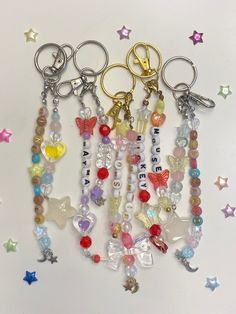 several key chains with charms attached to them on a white surface surrounded by stars and confetti