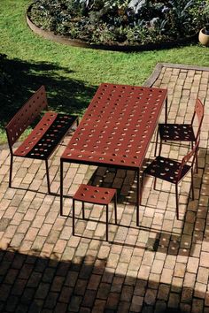 a table and chairs sitting on top of a brick patio next to a flower bed