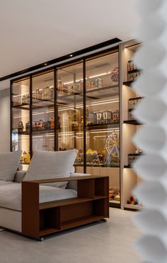 a living room filled with lots of furniture next to a wall mounted glass display case