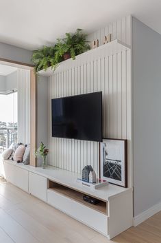 a flat screen tv sitting on top of a white entertainment center next to a window