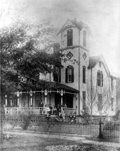 an old house with people sitting on the porch