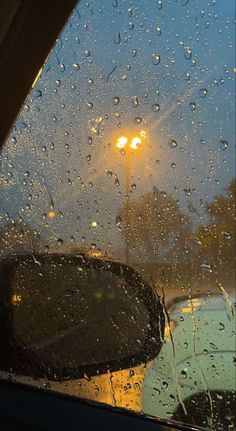 rain drops on the windshield of a car as it sits in front of a street light