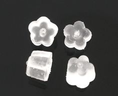 three pieces of plastic sitting on top of a black surface with white flowers in the middle