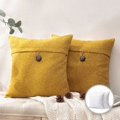 two yellow pillows sitting on top of a white bed next to a plant and a magazine