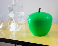 a green apple sitting on top of a table next to glasses and a glass vase