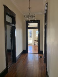 an empty room with wood floors and a chandelier