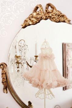 a dress is hanging on a stand in front of a mirror with chandelier