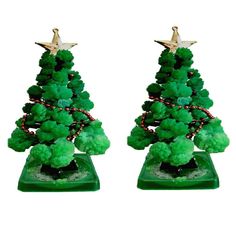 two green christmas trees with gold stars on top and red beads around the base, set against a white background