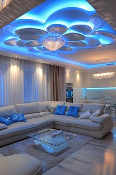 a living room filled with white furniture and blue lighting on the ceiling above it's windows